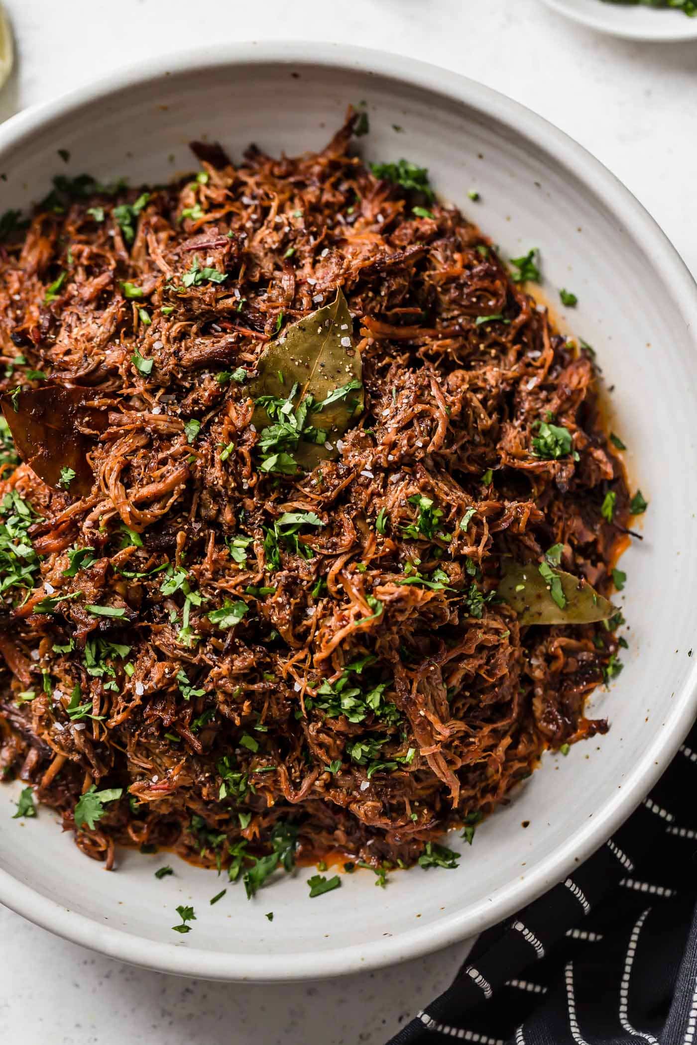 Slow Cooker Barbacoa Beef Slow cooker shredded barbacoa beef in a white serving bowl garnished with cilantro.