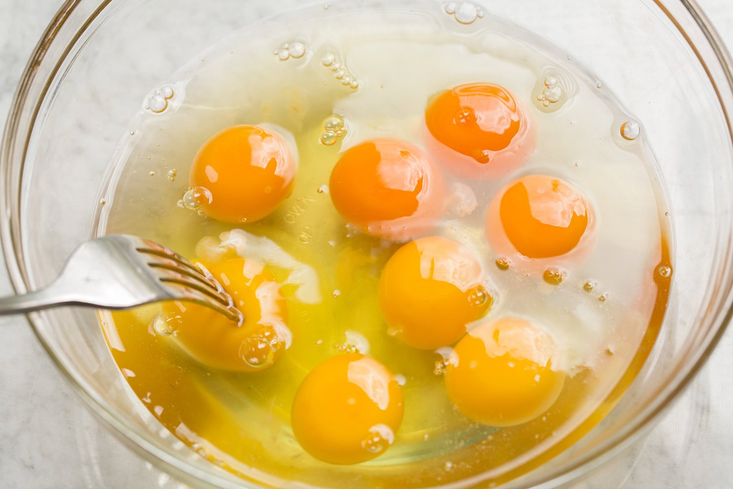 Breakfast Bowls Cracked eggs in a bowl shown before scrambling.