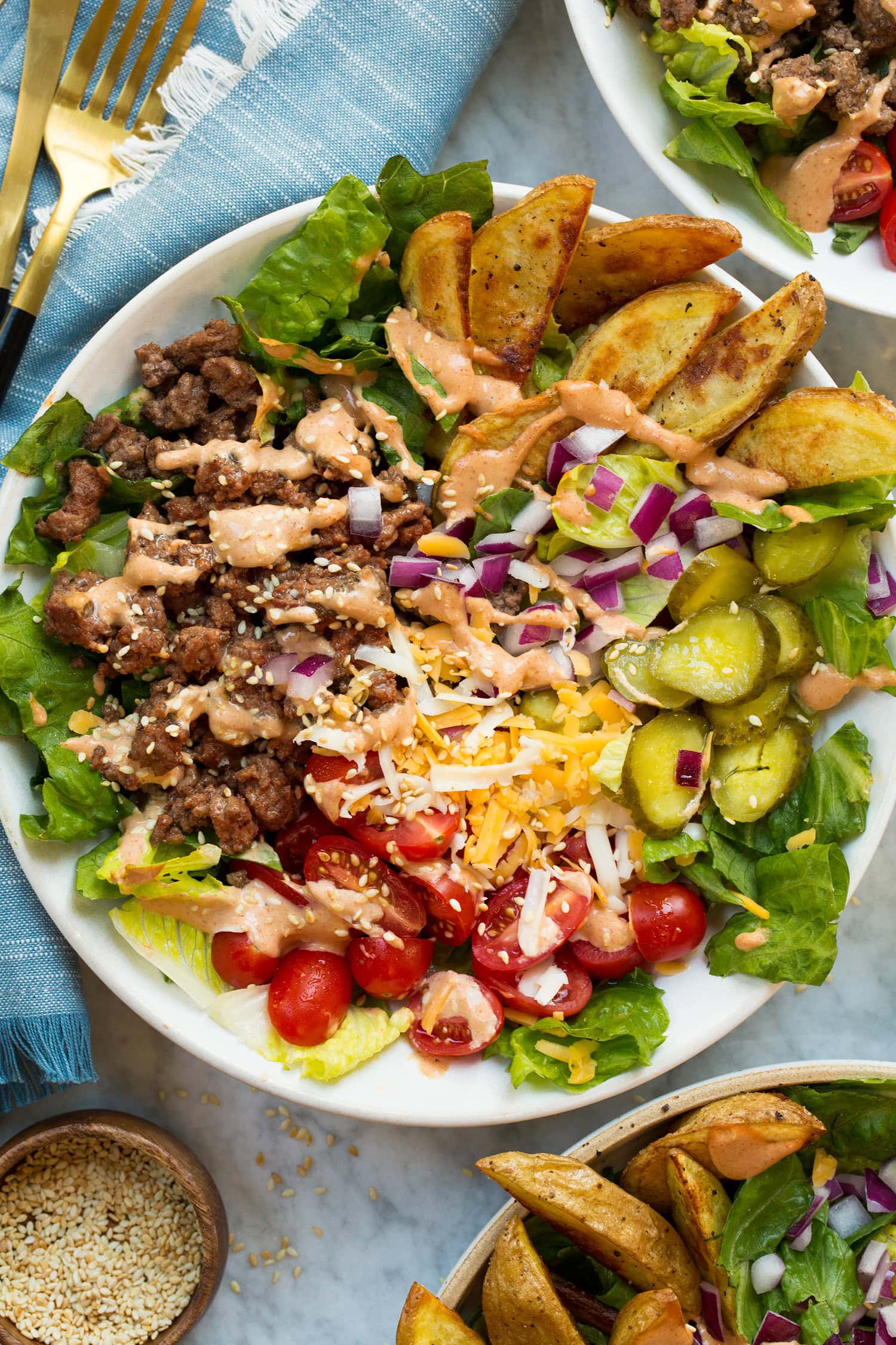 Burger Bowls Single serving burger bowl showing ground beef, pickles, tomatoes, cheese, onion, baked fries and lettuce.