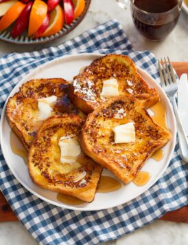 Four slices of buttermilk french toast with butter and maple syrup.