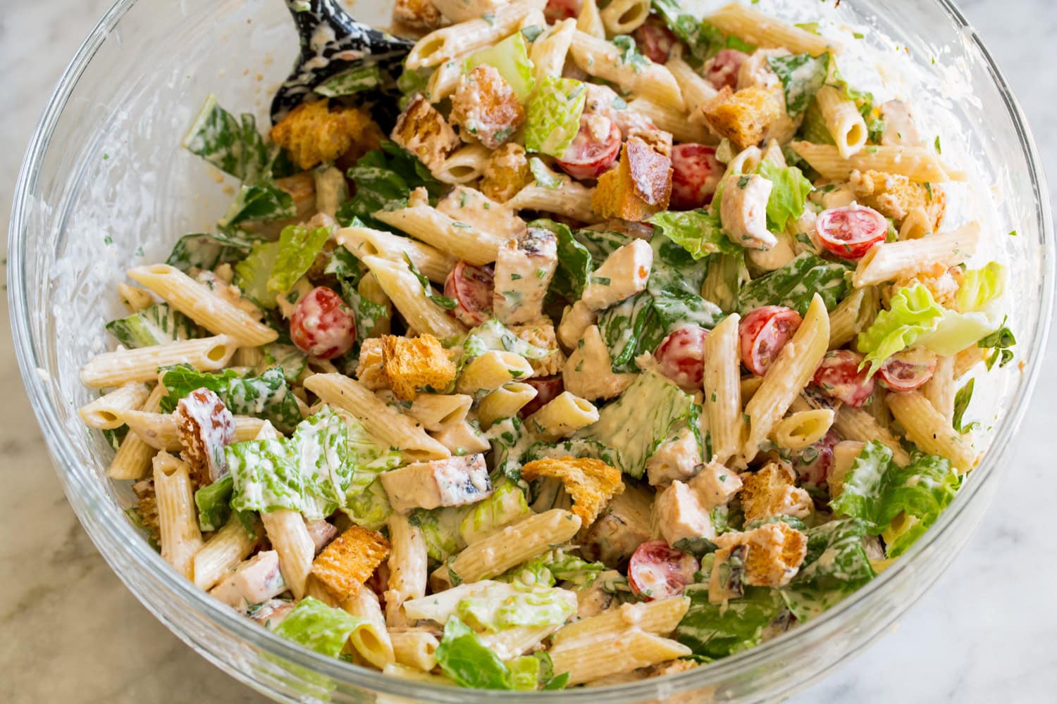 Chicken Caesar Pasta Salad Completed pasta salad in mixing bowl.