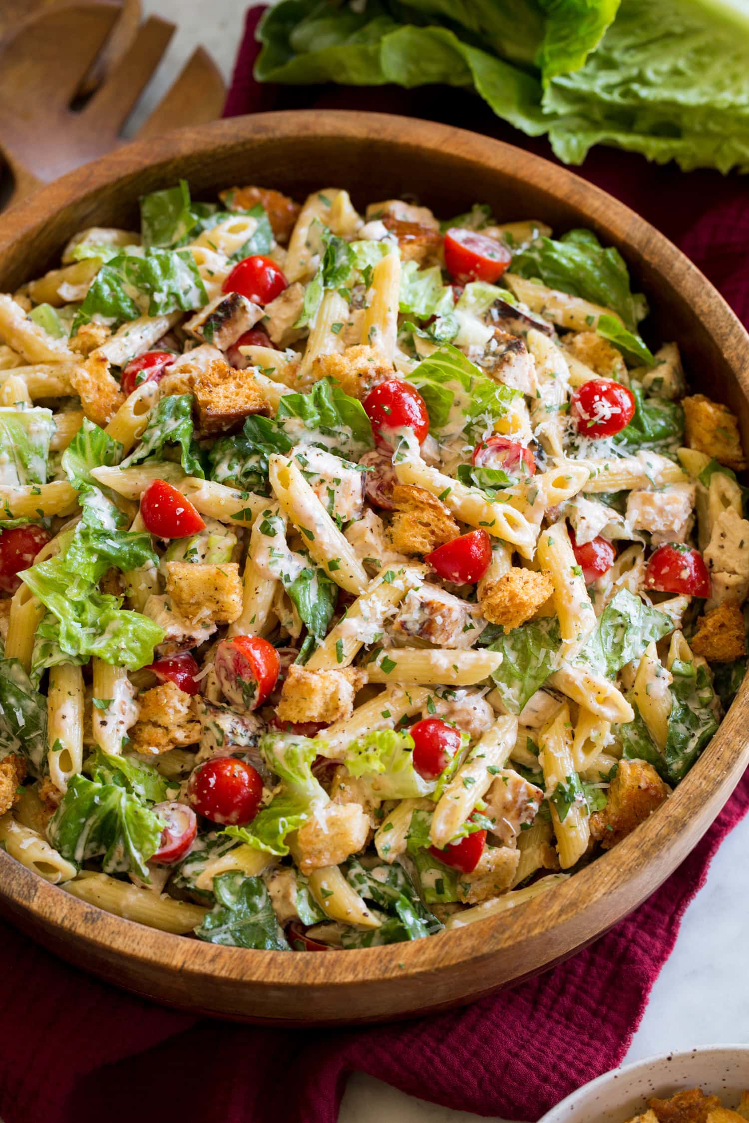 Chicken Caesar Pasta Salad Side angle shown of chicken caesar pasta salad with romaine lettuce, chicken, croutons, parmesan and tomatoes.