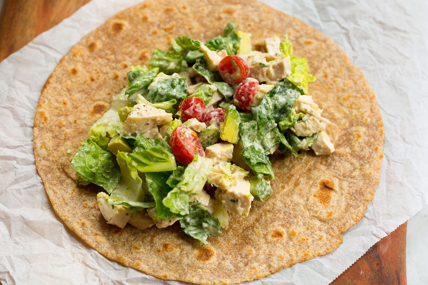 Chicken Caesar Wrap Chicken caesar salad layered over tortilla before wrapping.