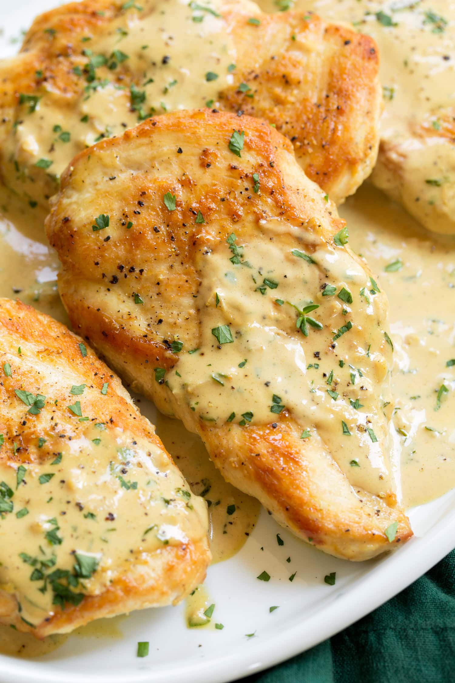 Creamy Dijon Mustard Chicken Golden brown chicken breast with mustard sauce and herbs shown close up.