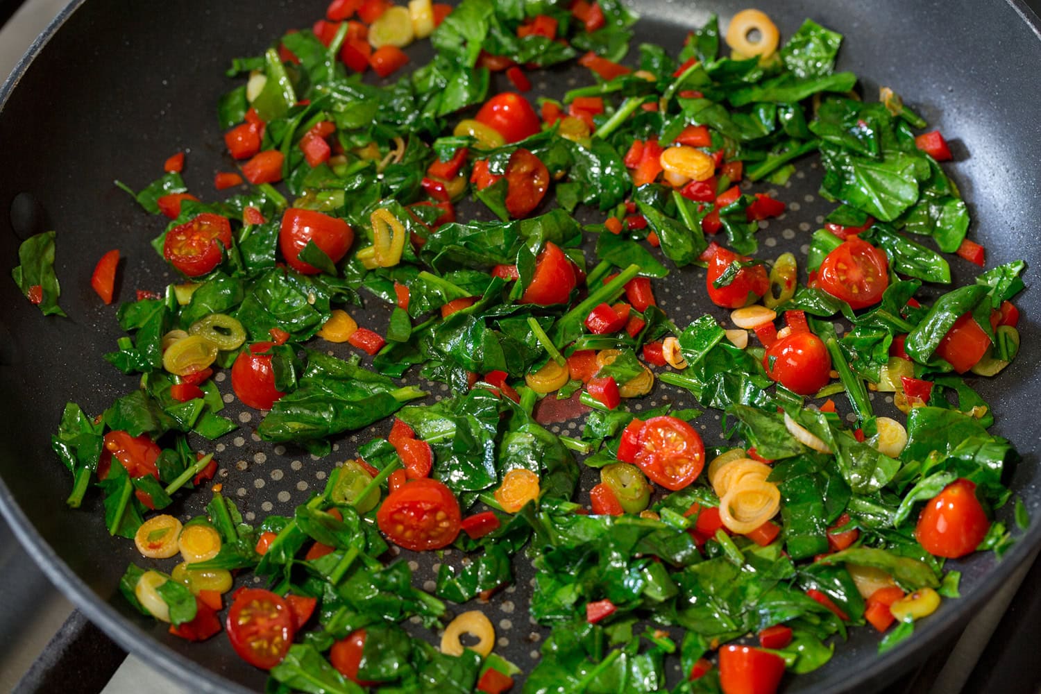 Egg White Omelette Spinach added to sauteed veggie mixture in skillet.