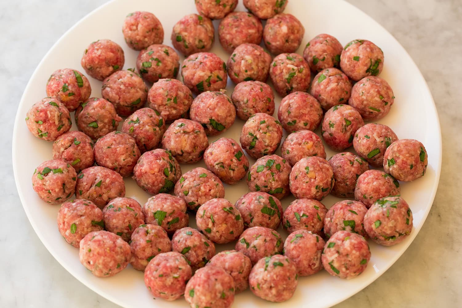 Italian Wedding Soup Formed mini Italian meatballs on a large plate.