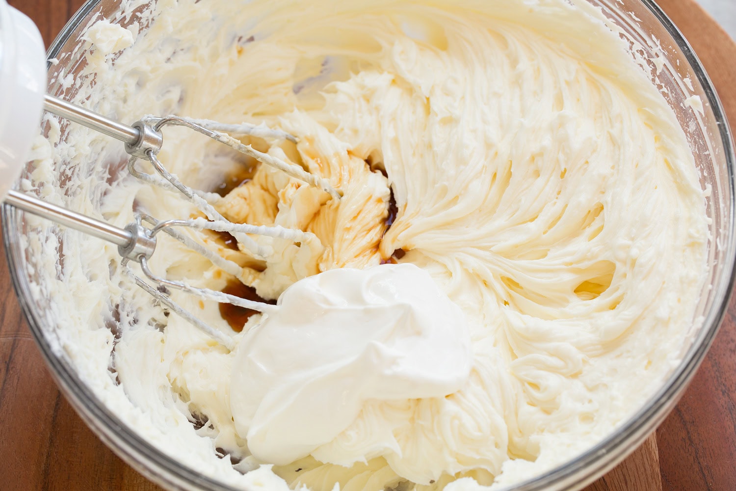 No Bake Cheesecake Sour cream and vanilla added to cream cheese mixture in glass bowl.