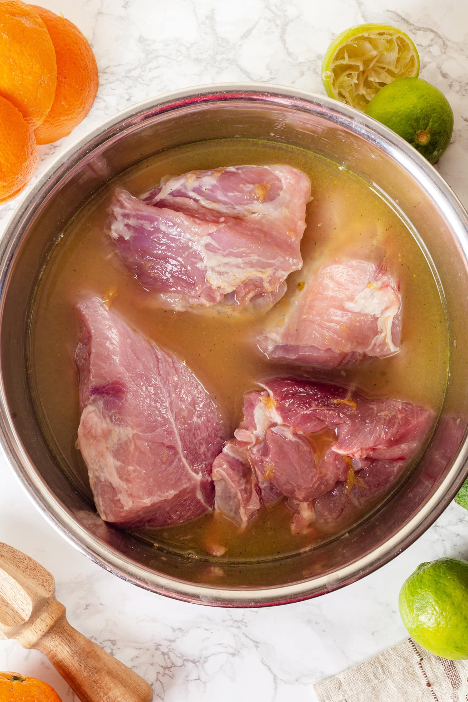 Carnitas Pork chunks in liquid in a stainless bowl.