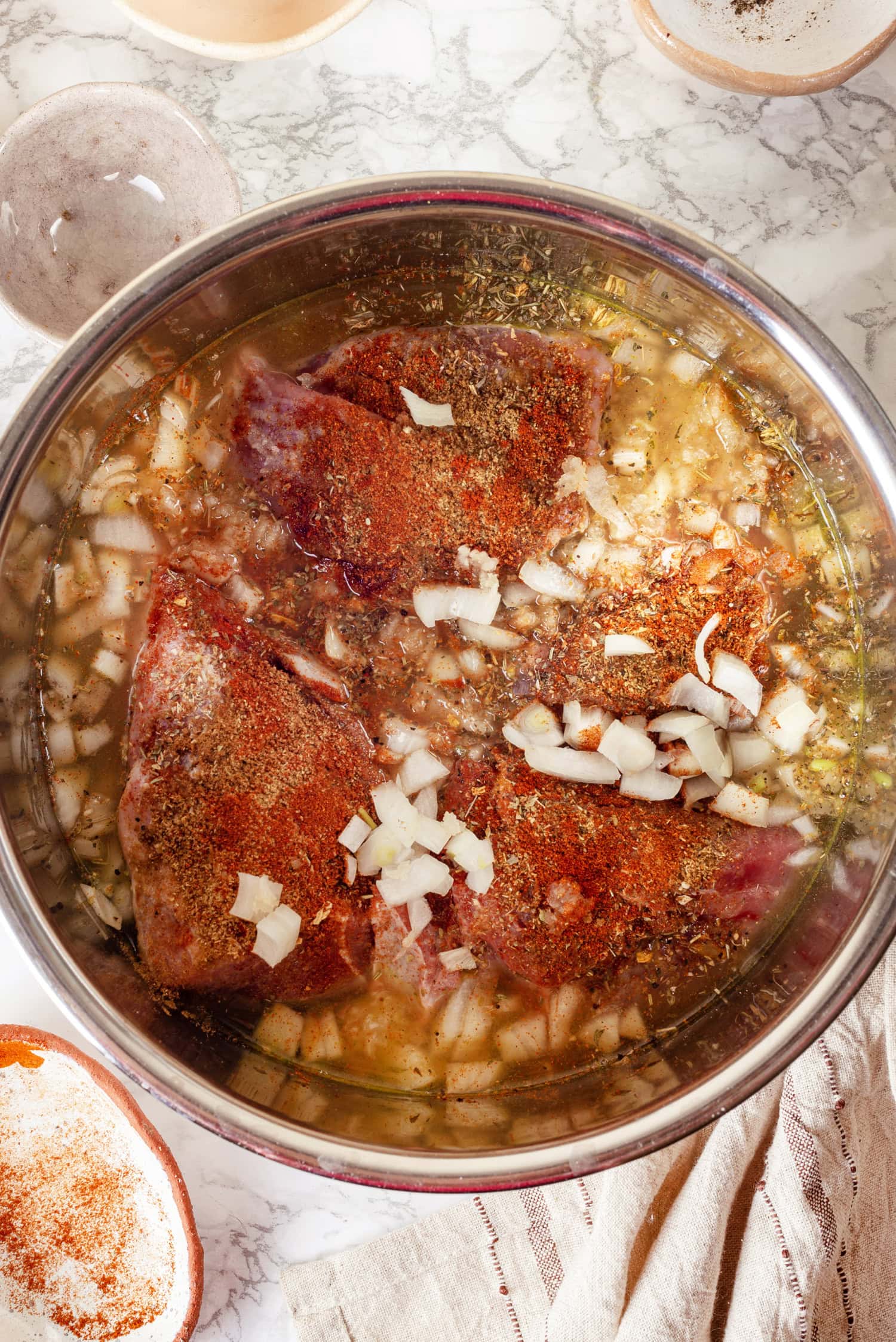 Carnitas Pork chunks in broth covered in Mexican spices and onion.