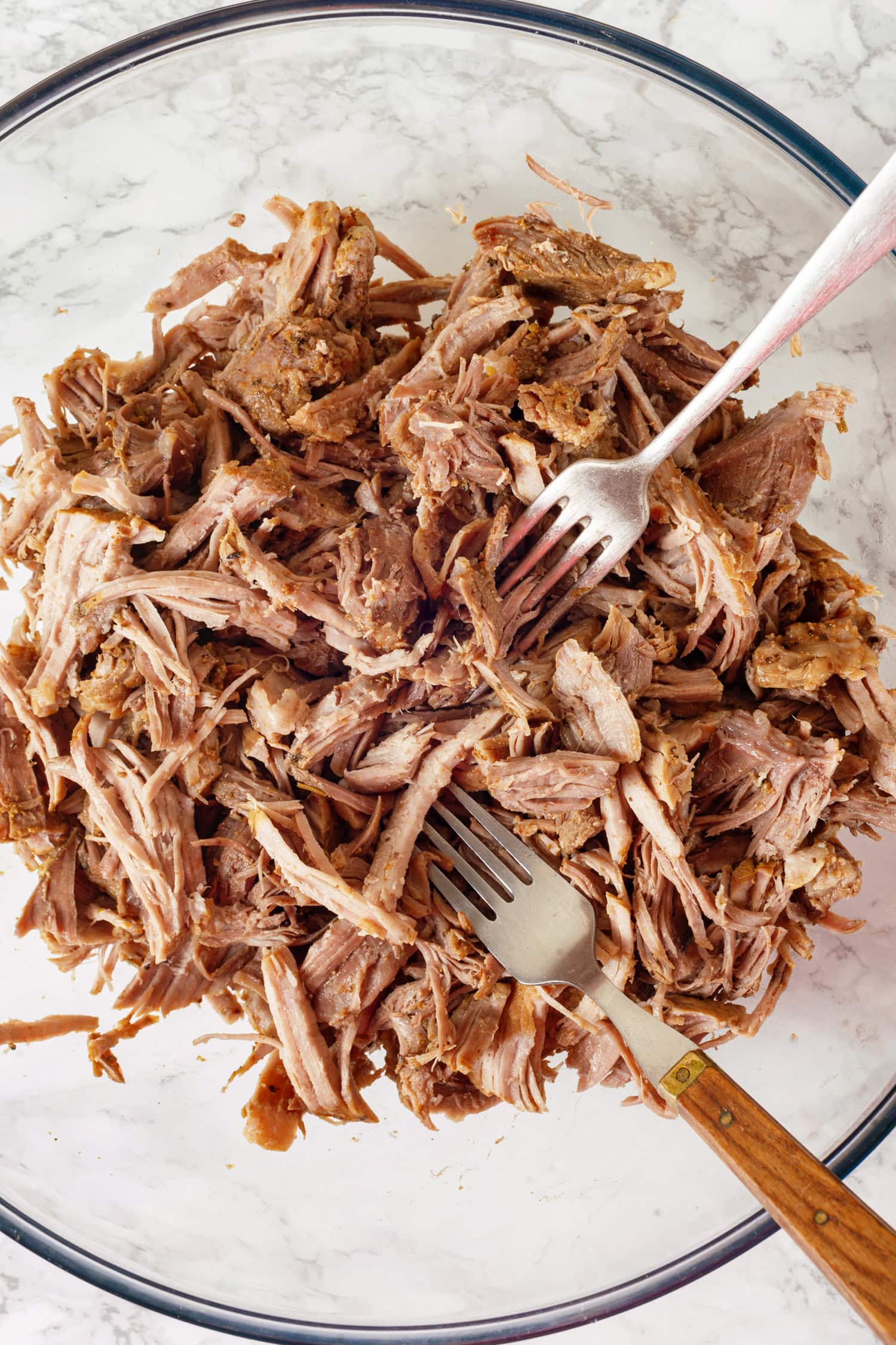 Pork Carnitas Shredding cooked pork in a bowl.