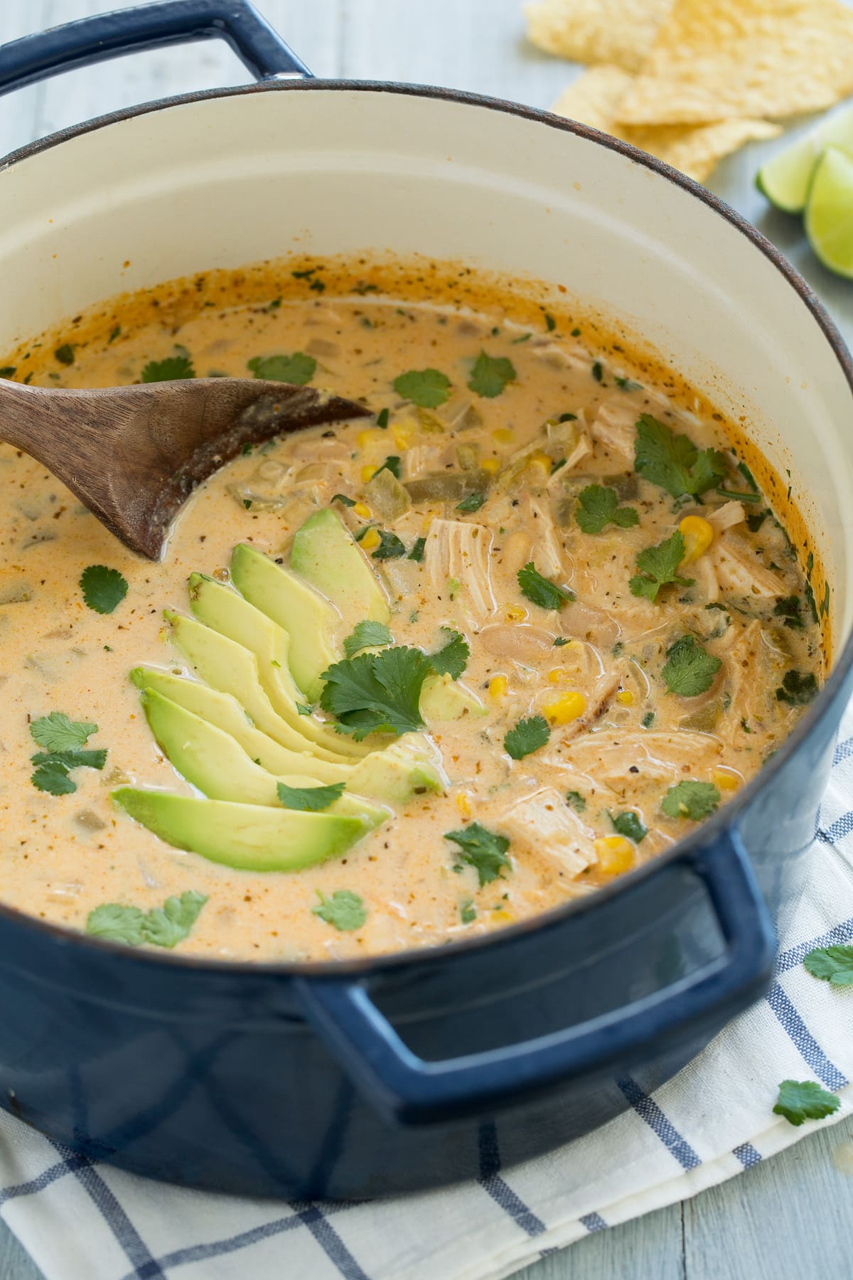 White Chicken Chili Navy blue pot full of white chicken chili. Chili includes pieces of chicken, pinto beans, corn, green chilies and a creamy broth, it is garnished with avocado and cilantro.